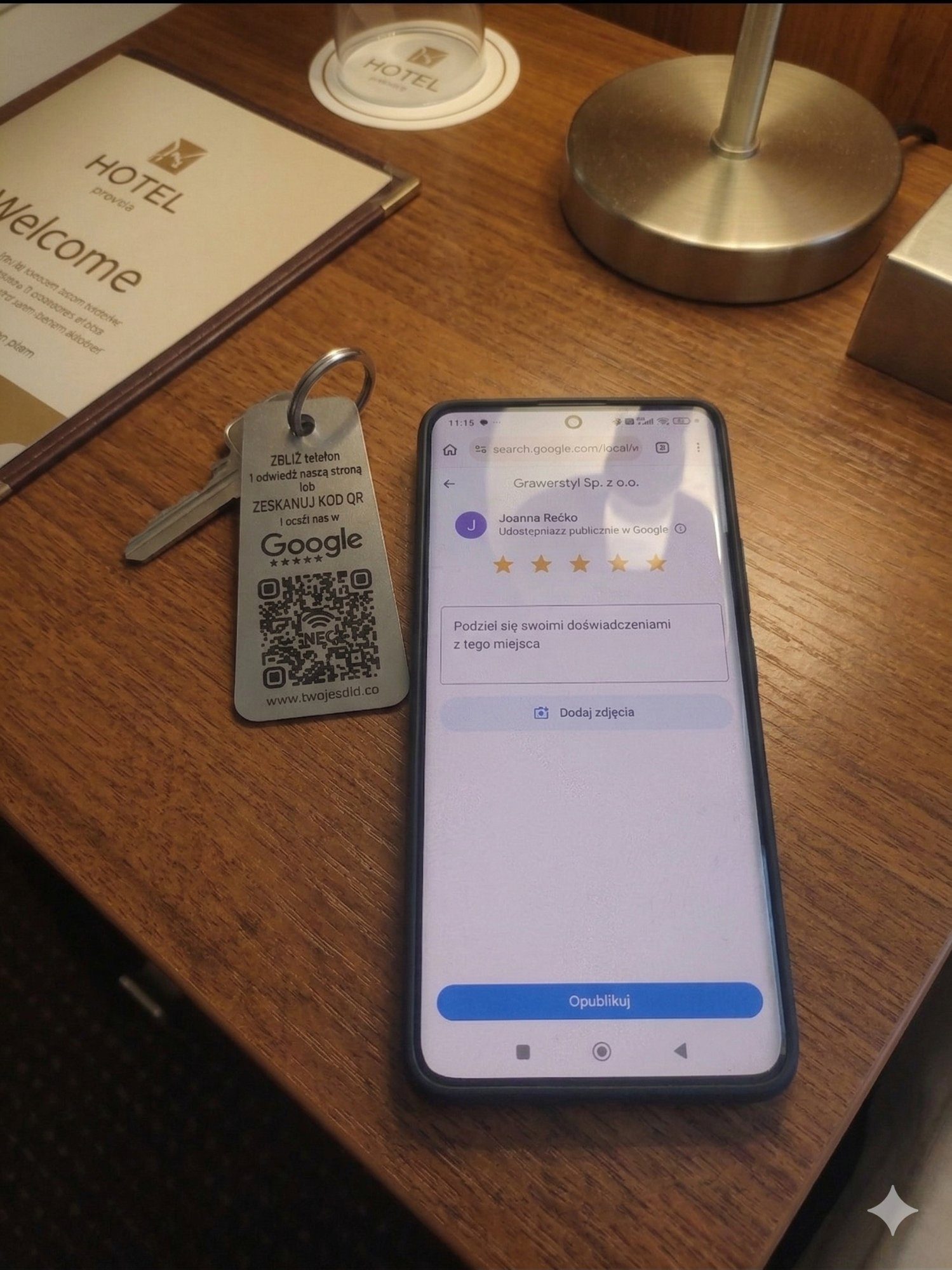 Smartfon z formularzem opinii Google obok breloka hotelowego
